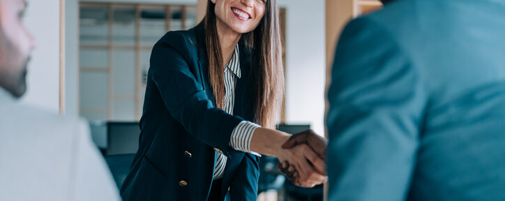 Professional business consultation showing female accountant shaking hands with business owner in modern office setting, representing the benefits of hiring outside accounting services